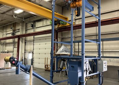 Bulk bag unloader with dual massaging paddles and a screw conveyor to transfer material to a dosing feeder.