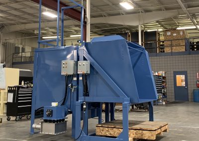 Heavy-duty Gaylord container dumper mounted on a riser stand, positioned to discharge material into a collection bin equipped with a vacuum takeaway box for downstream conveying.