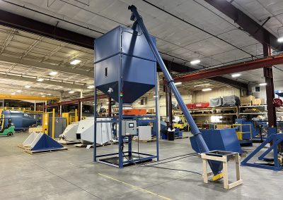 Screw conveyor and hopper for dry bulk material pack-out and integrates with a larger system