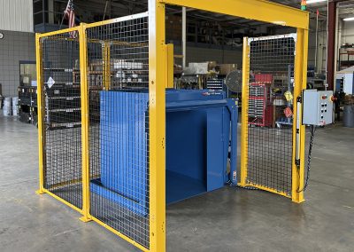 Side-load dumper with safety caging and light screen, engineered for space limitation or unique layout, allowing containers to discharge left or right. Features self-contained hydraulic motor/gear pump and modular cartridge-style valves for maintenance-friendly operation.